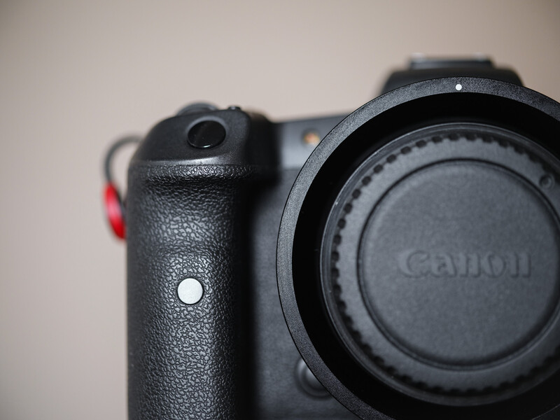 Canon DSLR camera body with grip and lens cap, photographed against a neutral background.