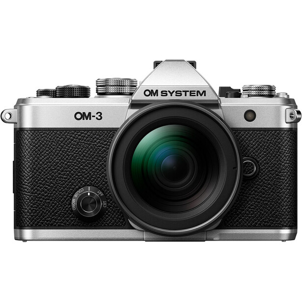 OM System OM-3 mirrorless camera with silver top plate and black textured body, featuring a mounted green-tinted lens.