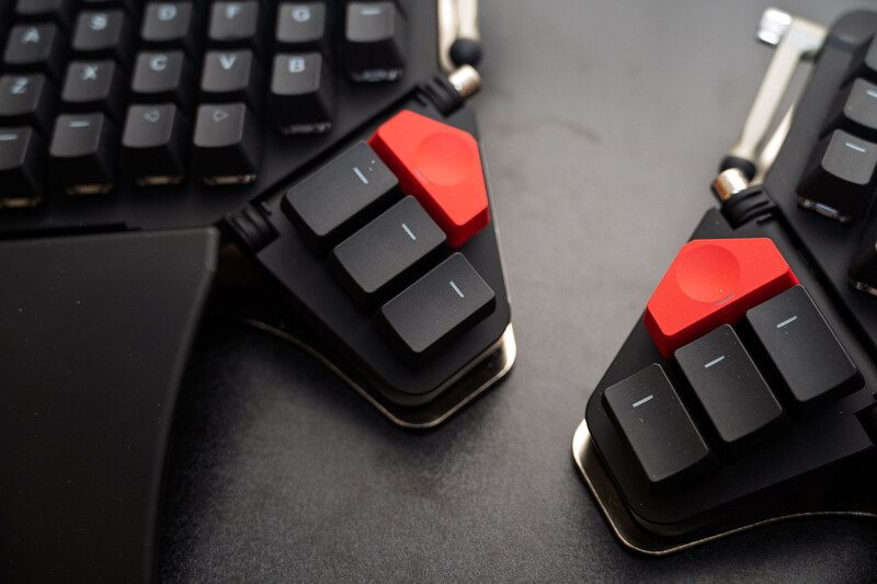 Two black mechanical keyboards with red keycap accents viewed from above on a gray surface.
