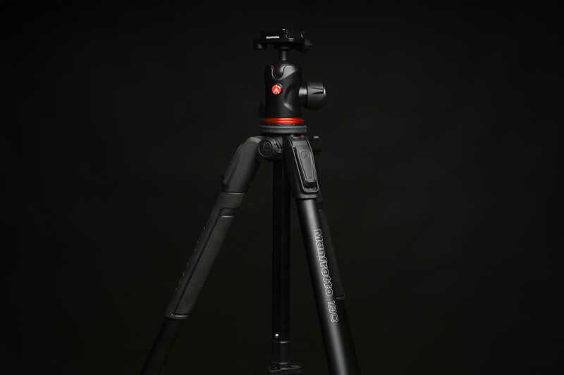 Professional tripod with ball head and red accent details against a black background.