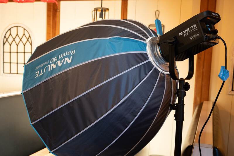 Large spherical softbox with blue and black ribbed fabric attached to a studio light head.