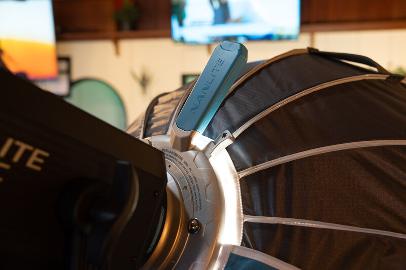 Close-up of studio lighting modifier with white housing and blue adjustment handle mounted on light fixture.