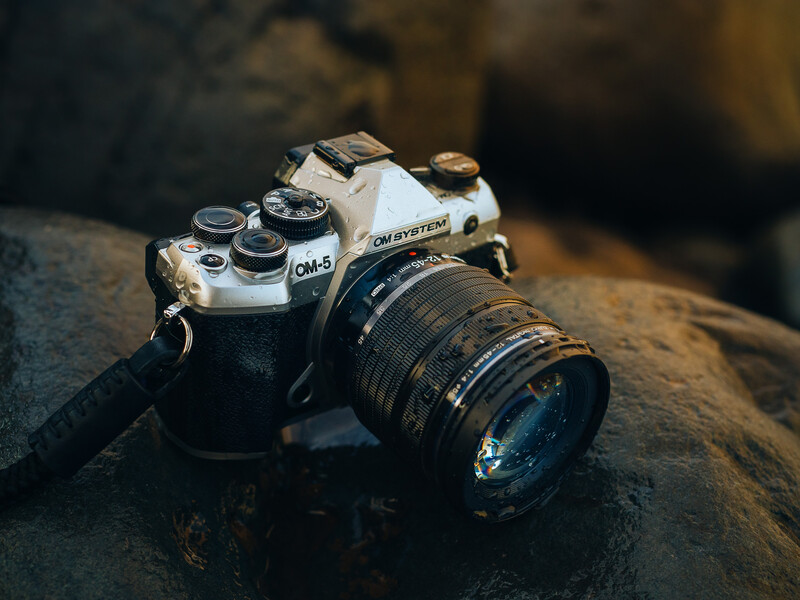 Vintage film SLR camera with standard lens mounted on weathered stone surface.