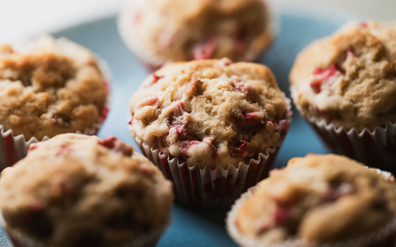 Strawberry muffins in brown paper liners arranged on a blue plate with shallow depth of field.