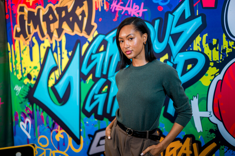Model standing in front of wall covered in graffiti 