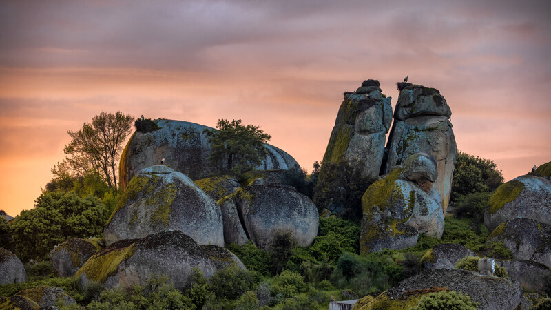 Rock formations standing in front of a colourful sunrise sky