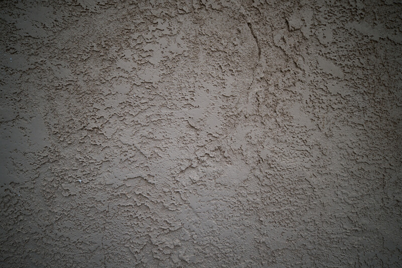 Close-up of rough concrete or cement surface with uneven texture and natural weathering patterns.