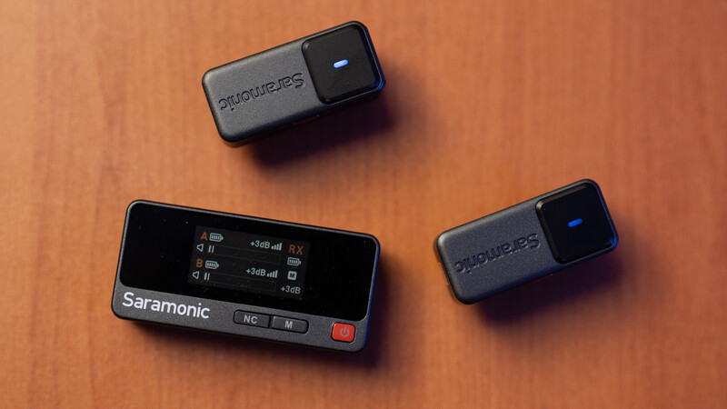Saramonic wireless microphone system with receiver unit and two transmitter modules on orange background.