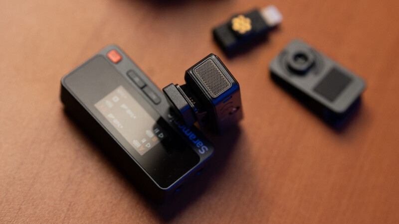 Compact wireless microphone system with receiver and transmitter units on tan surface.