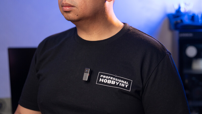 Man wearing black t-shirt with "Professional Hobbyist" text graphic against blue-lit background.