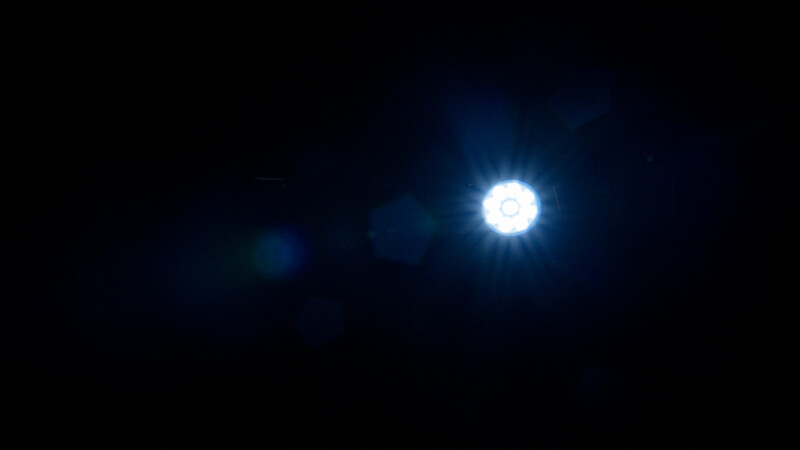 Bright celestial body with lens flare against deep blue-black night sky.
