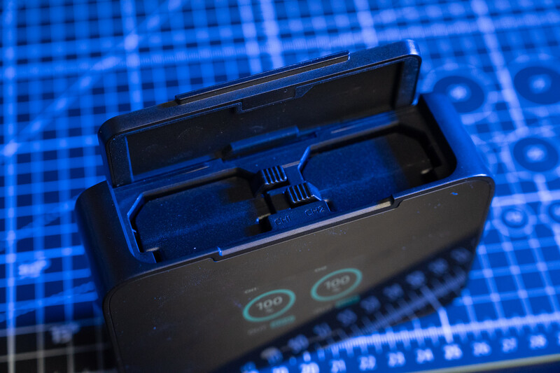 Open charging case with two wireless earbuds inside, displayed on a blue digital circuit board background.