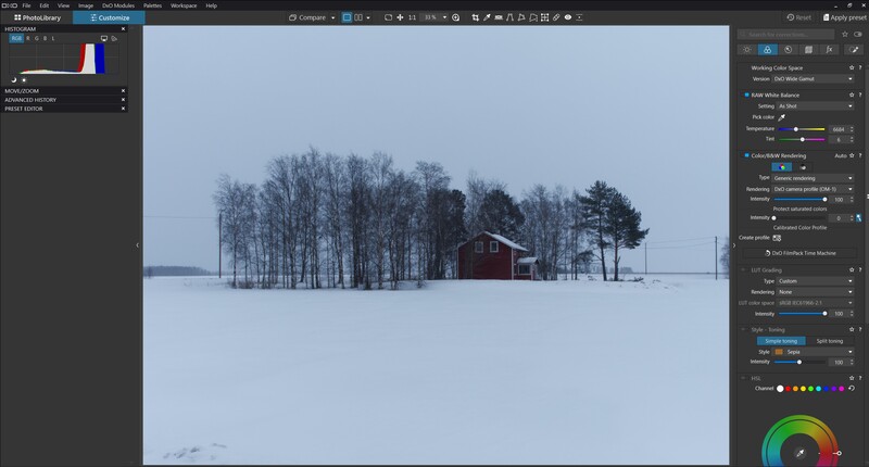 Snowy winter landscape with a red barn and bare trees in the distance under overcast sky.