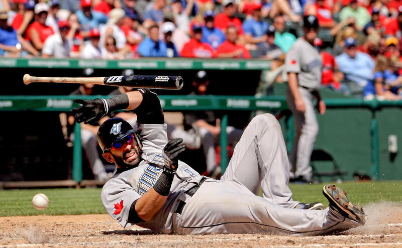 Baseball player sliding into base during a game, captured mid-motion on the infield dirt.