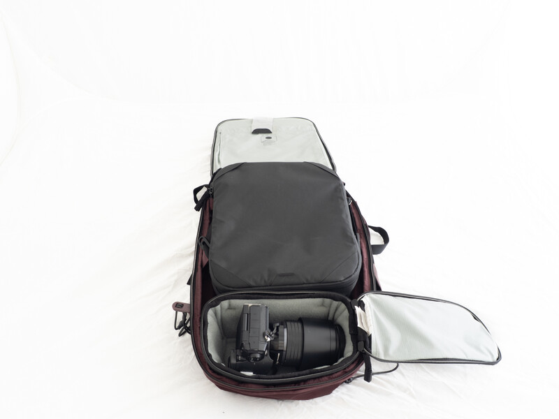 Open photography camera backpack displaying organized gear compartments and a padded camera lens storage area.