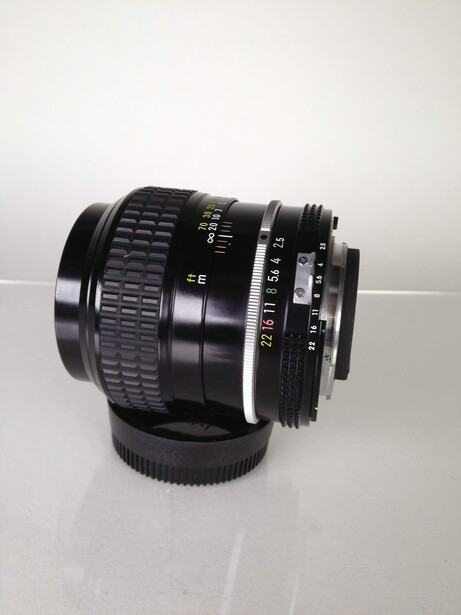 Vintage manual focus lens with aperture ring and focus helicoid, mounted on white surface.
