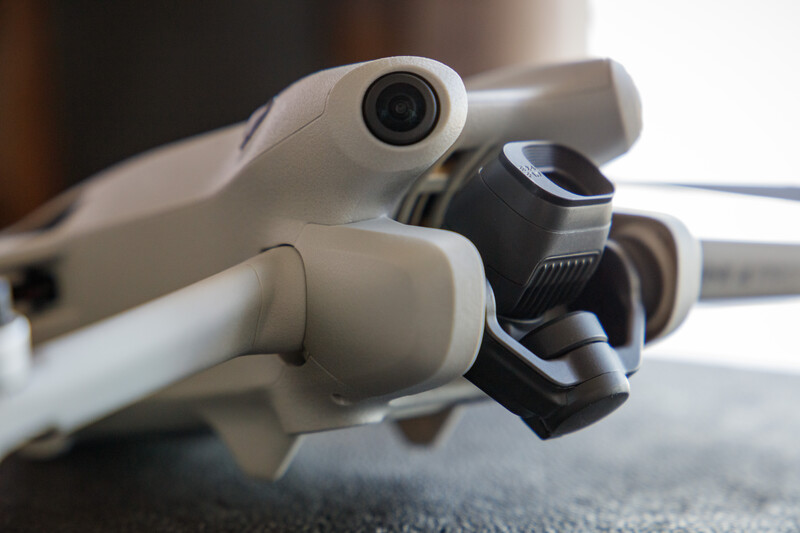 Close-up detail of a camera drone's gimbal, camera lens, and mechanical arm components.