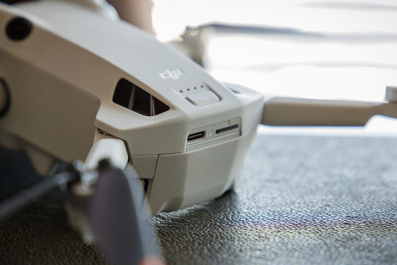 Close-up of a white drone's control arm and USB ports with charging indicator lights visible.
