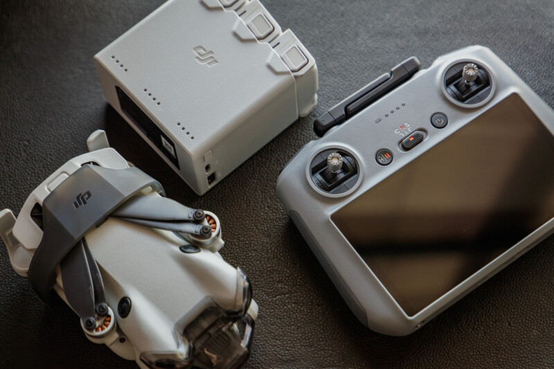 DJI drone controller and accessories laid out on gray fabric surface.
