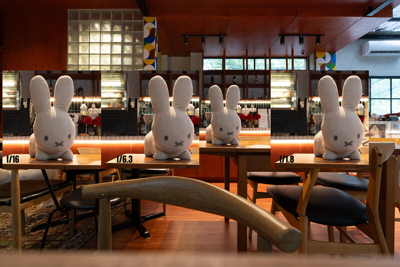 Four white rabbit figurines displayed on a wooden counter in a modern interior space with warm lighting.