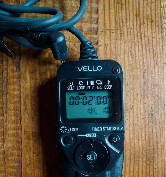 Vello digital timer with blue cord coiled on wooden surface, displaying 00:02:00 on LCD screen.
