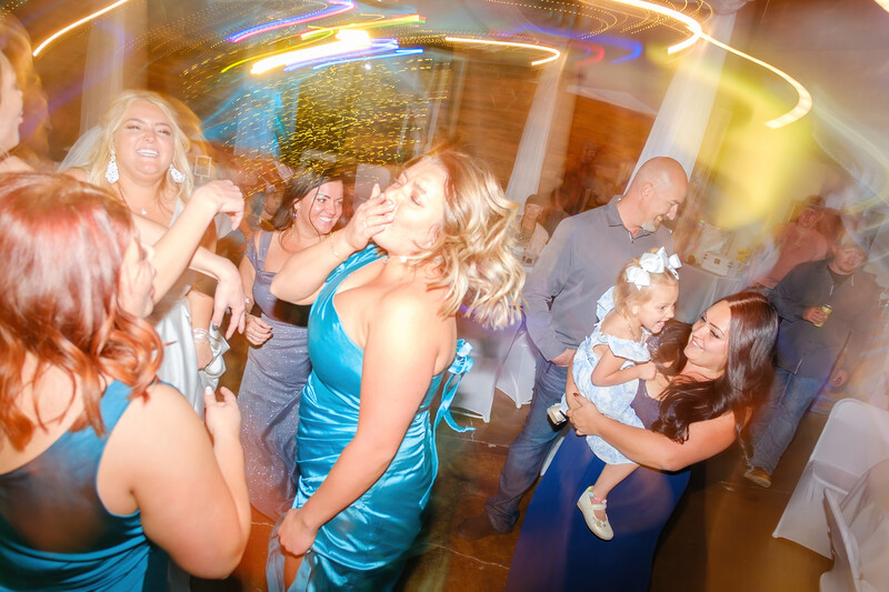 Group of people dancing and celebrating at an indoor event with warm golden lighting.
