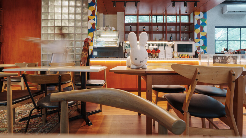 Modern café interior with wooden furniture, warm orange walls, and natural window light.