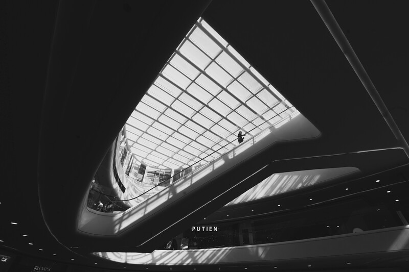 Upward view of a modern architectural interior with geometric skylight and dramatic shadows in black and white.