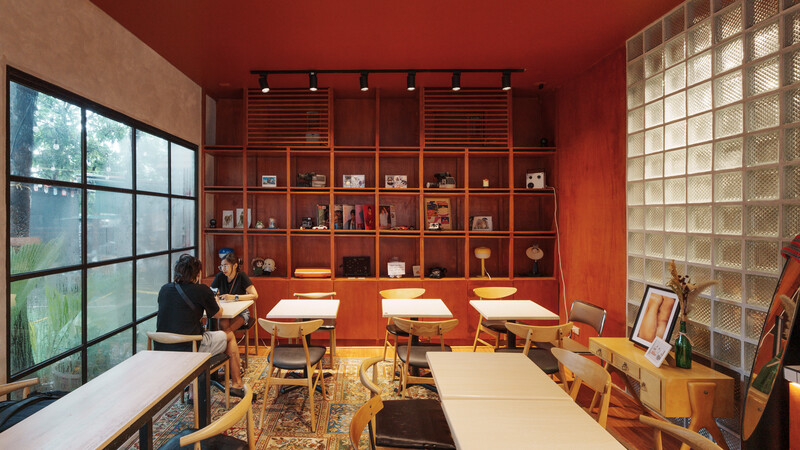 Modern office interior with warm wood cabinetry, glass block wall, and natural light from gridded windows.