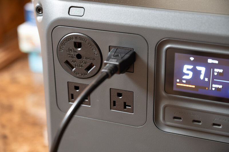 Close-up of a power outlet panel with a plugged-in cable and digital display showing 57 degrees Fahrenheit.