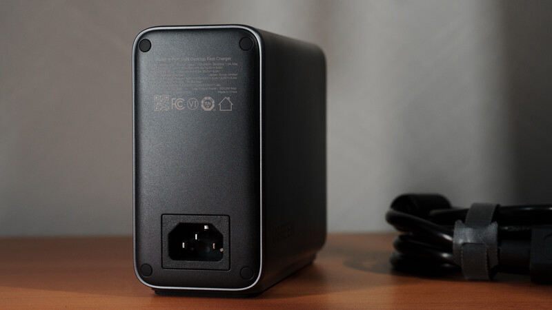 Black compact device with power inlet and small icons displayed on back panel.