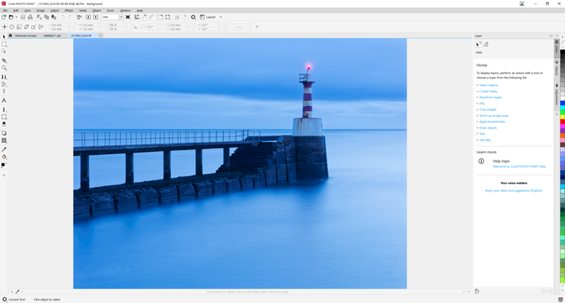 Lighthouse on a stone pier extending into calm blue ocean at twilight.