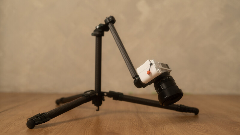 Articulating arm with ball head mounted on tripod-style stand holding small softbox.