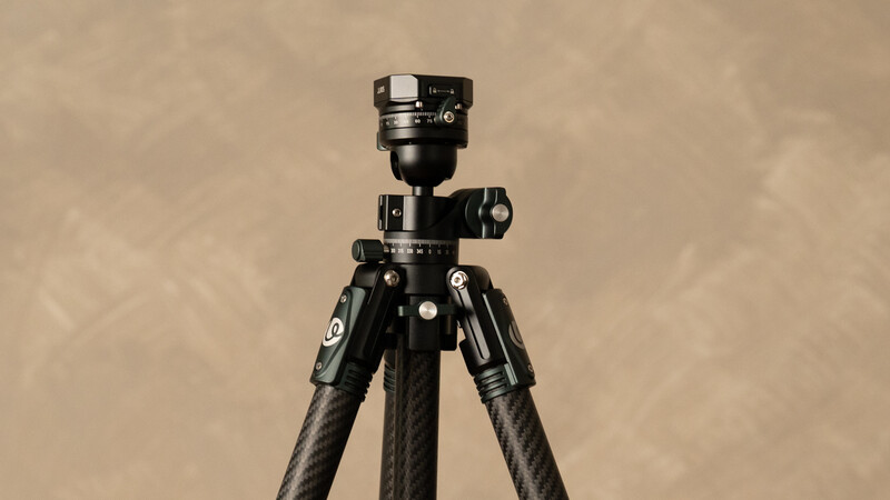 Carbon fiber tripod with ball head and spirit level mounted on neutral background.