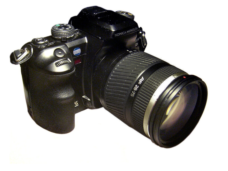 Black DSLR camera with attached zoom lens on white background.