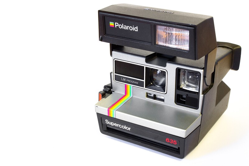 Polaroid Supercolor 635 instant camera with tan and black body and rainbow stripe film slot.