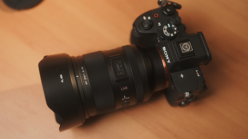 Sony mirrorless camera with telephoto lens mounted on tan-colored surface.