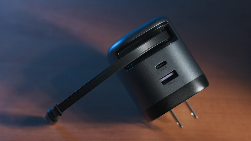 Dual-port USB wall charger with attached cable against dramatic sunset sky backdrop.