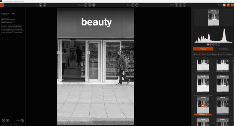 Black and white photograph of a person walking past a storefront with 'beauty' signage.