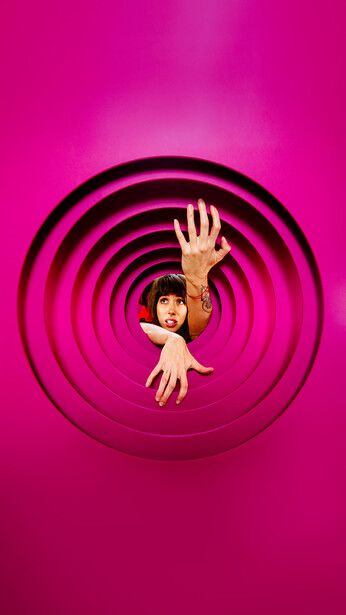Person suspended in concentric magenta circles against a bright pink background.