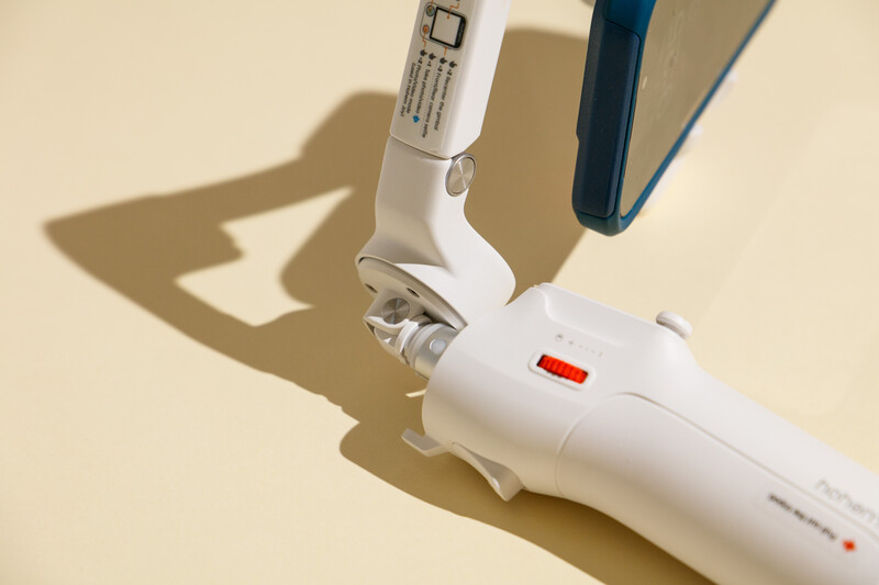 White electric toothbrush with blue accents casting a shadow on beige background.