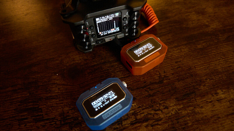 Three portable audio devices with screens arranged on a wooden surface.