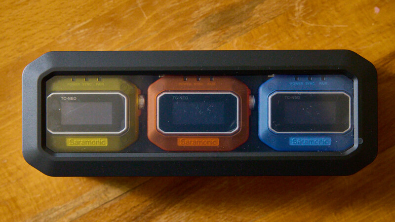 Three vintage electronic calculators in yellow, orange, and blue housed in a black display case.