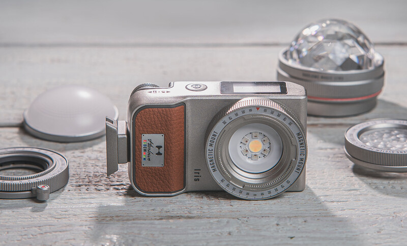 Vintage rangefinder camera with brown leather body surrounded by lens attachments and accessories on gray surface.