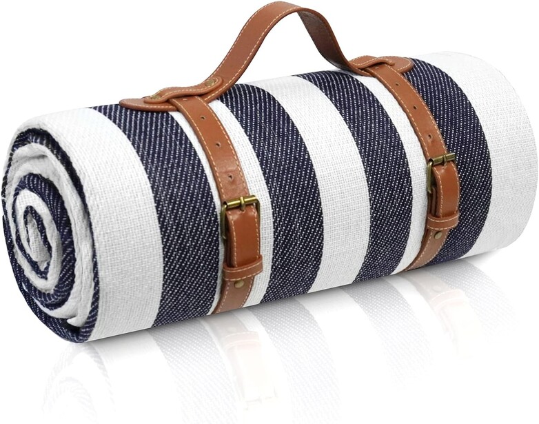 Rolled striped picnic blanket with brown leather carrying handles and shoulder strap.