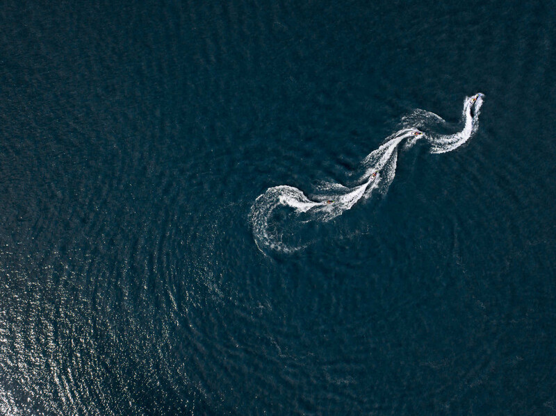 Aerial view of a whale's wake pattern curving through deep blue ocean water.