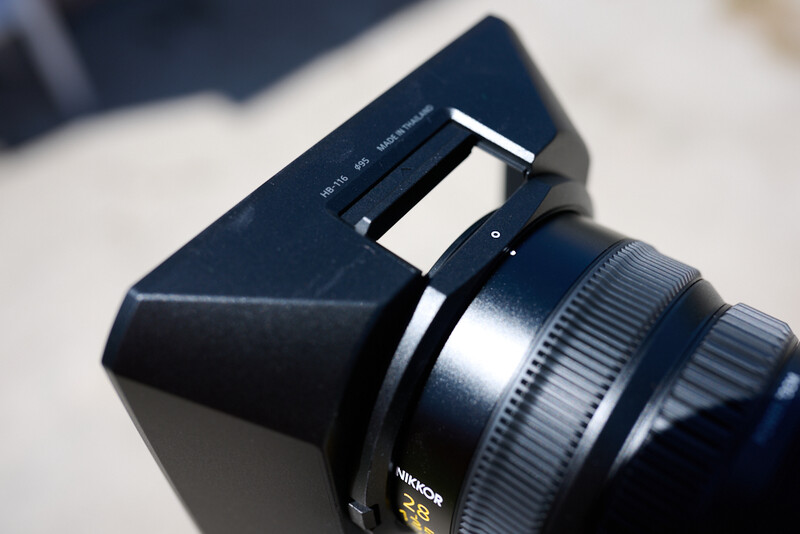 Nikon lens with black lens hood attached, showing focusing ring and distance scale markings.