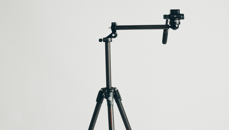 Professional camera jib arm mounted on tripod against neutral background.