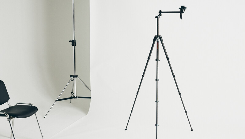Two tripod-mounted lighting stands shown side by side against a white wall and floor.