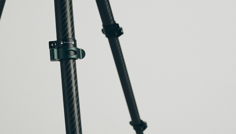 Two dark carbon fiber or composite poles against a light background, one with a metal mounting bracket or clamp.